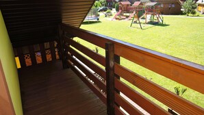 Eine Holzterrasse mit Blick auf einen Spielplatz und Häuser im Hintergrund.