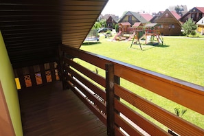 Eine Holzterrasse mit Blick auf einen Spielplatz und Häuser im Hintergrund.