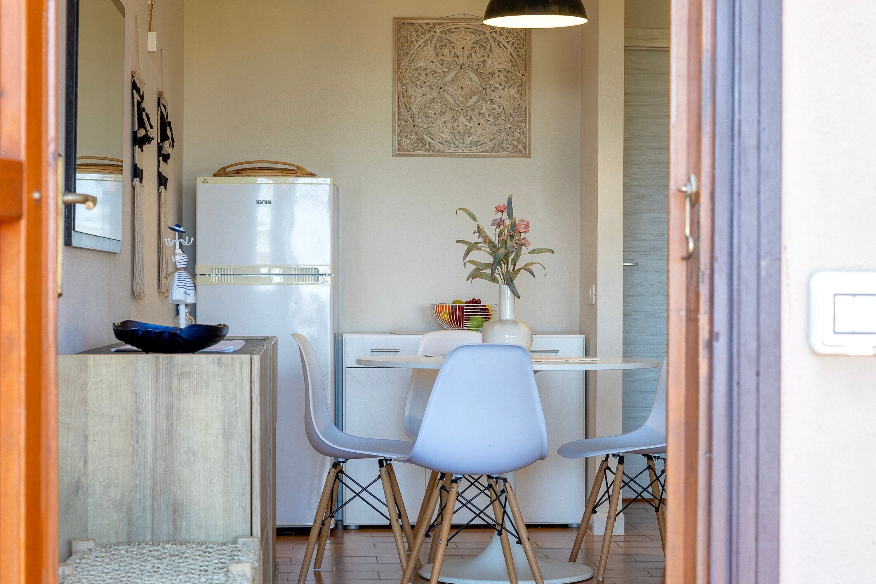 Una cucina funzionale con frigorifero, un tavolo da pranzo con sedie e un elemento decorativo a parete.
