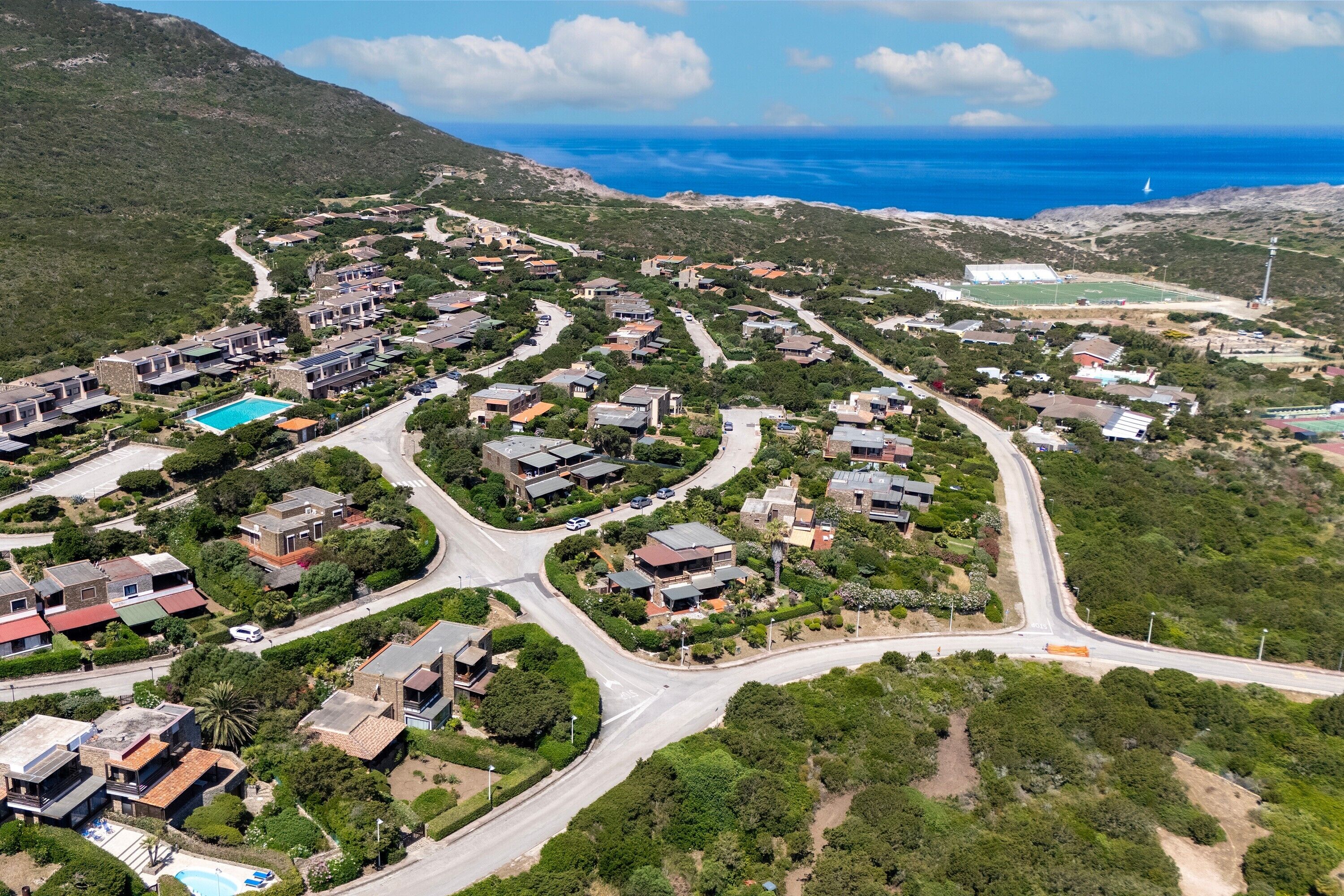 Quartiere residenziale con case, strade e una piscina.