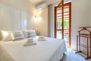 Una camera d'albergo con un letto, cuscini, un comodino, una lampada a sospensione e vista attraverso una porta.