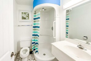 A bathroom with a shower, toilet, sink, and a framed picture on the wall. - King Bed Smoking | Albany (Albany GA)