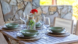 Una mesa dispuesta con cuencos verdes, copas de vino y un florero con una flor roja.