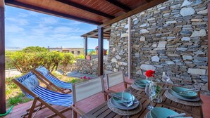 Un espacio de descanso al aire libre con techo, una pared de piedra, una hamaca y una mesa lista para comer.