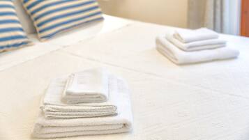 A neatly made bed with white and blue striped pillows and folded white towels.