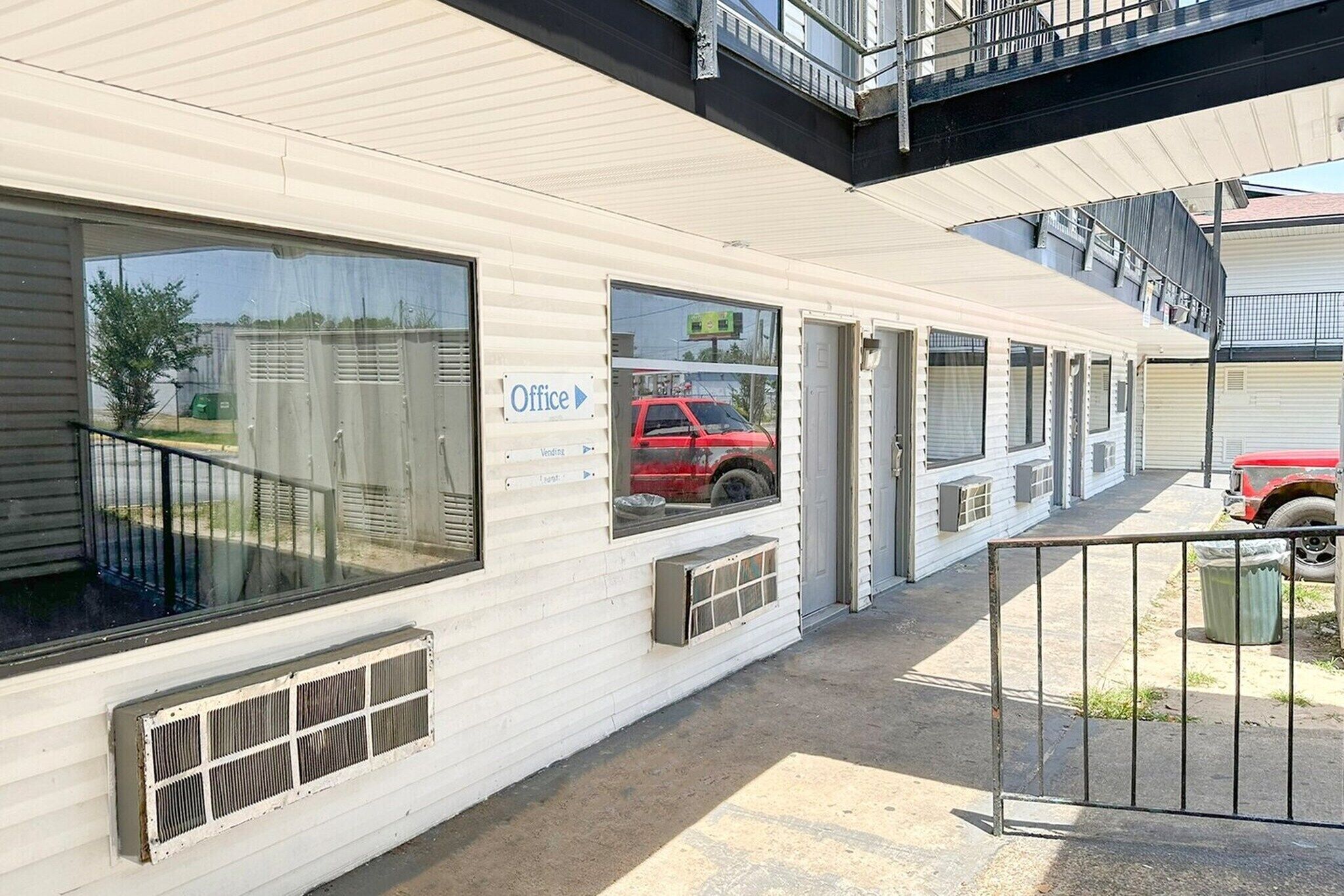 Fila de cases mòbils blanques amb grans finestres, una unitat petita de aire condicionat al costat i un cotxe vermell estacionat a la zona d'aparcament.