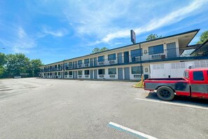 Ein Motel mit einer zweistöckigen Struktur, ein roter Pick-up-Truck davor, und ein klarer, blauer Himmel.