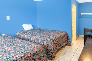 Una habitación con dos camas, una puerta y una mesita.