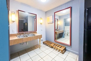 Ein Badezimmer mit zwei Waschbecken, einer Holzhilfe und einem Spiegel mit rotem Rahmen.