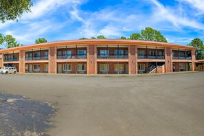 A multi-story motel with a brick facade, multiple balconies, and a parking lot.