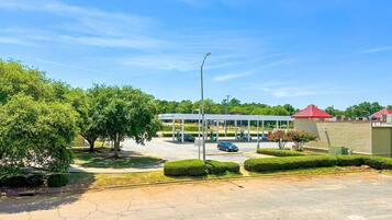 Una estación de servicio con varias bombas de combustible, un área de estacionamiento techada y un edificio con tejados rojos.