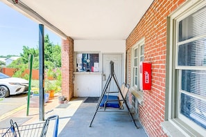 Un espacio exterior cubierto con un muro de ladrillo, una puerta, un banco y un letrero rojo.