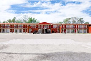 Un motel de dos pisos con ventanas de marco rojo y una entrada central.
