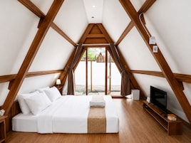 Un dormitorio con una cama grande, vigas de madera, un televisor y una ventana.