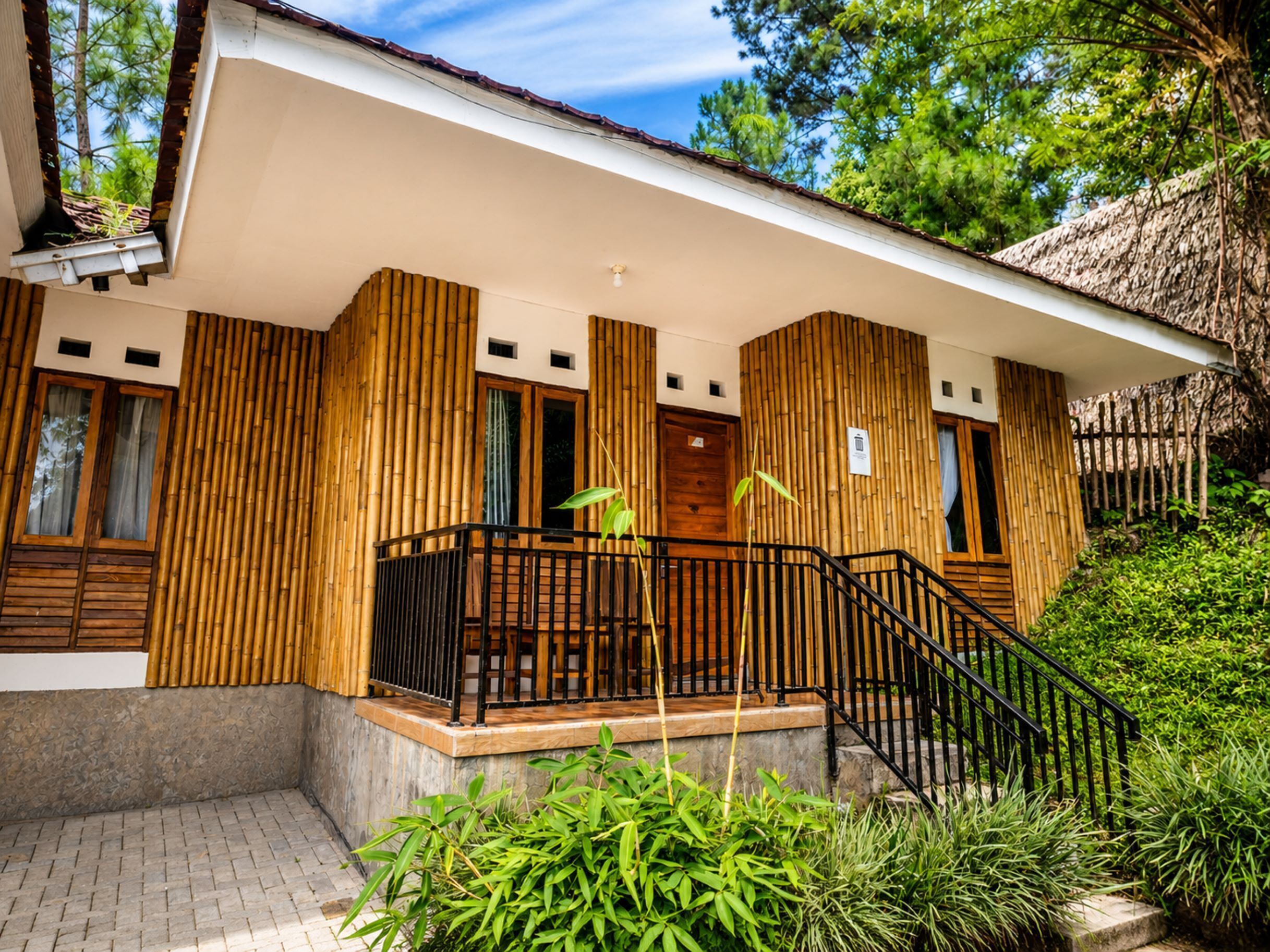 A modern building with a wooden facade, a balcony with black railings, and a staircase leading to the entrance.