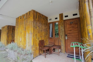 A room with a bamboo wall, a wooden door, and two wooden chairs.