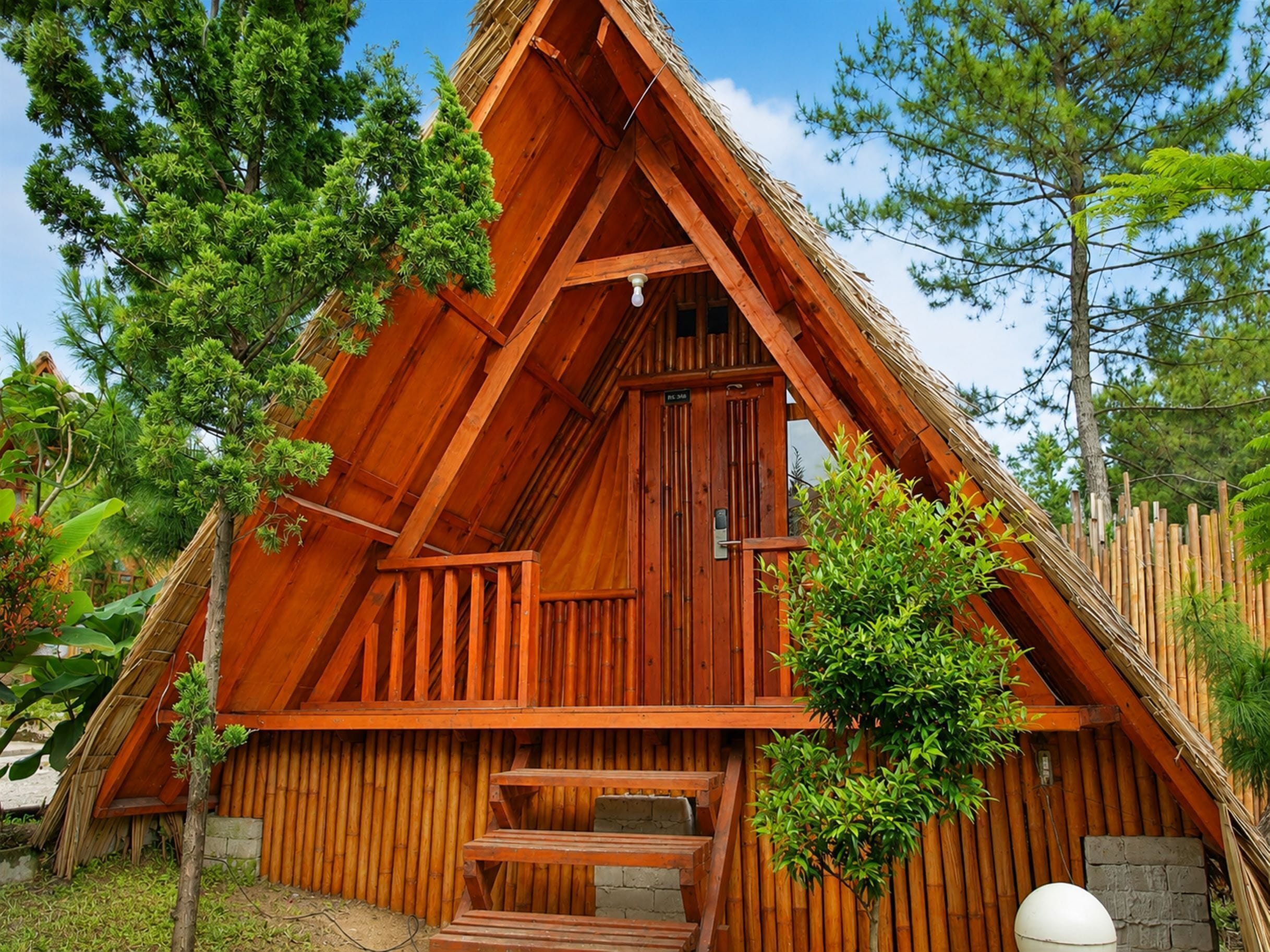 A wooden cabin with a steeply pitched roof, a front porch, and a door.