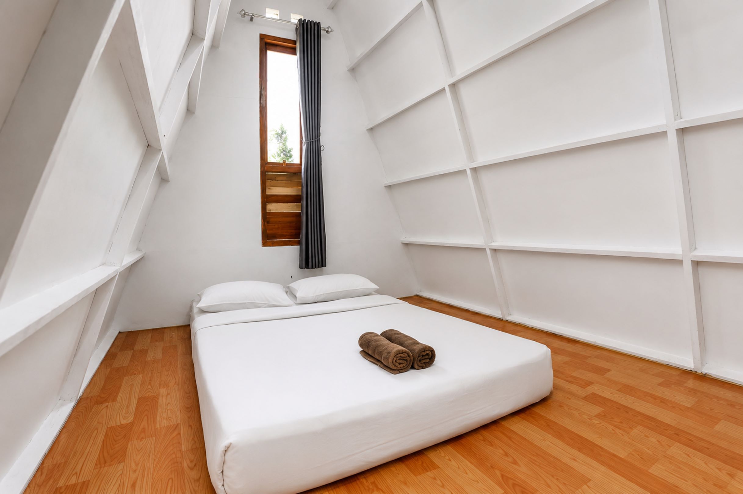 Un dormitorio con cama, ventana y pared blanca con diseño de cuadrícula.