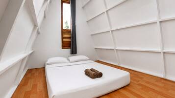 Un dormitorio con cama, ventana y pared blanca con diseño de cuadrícula.