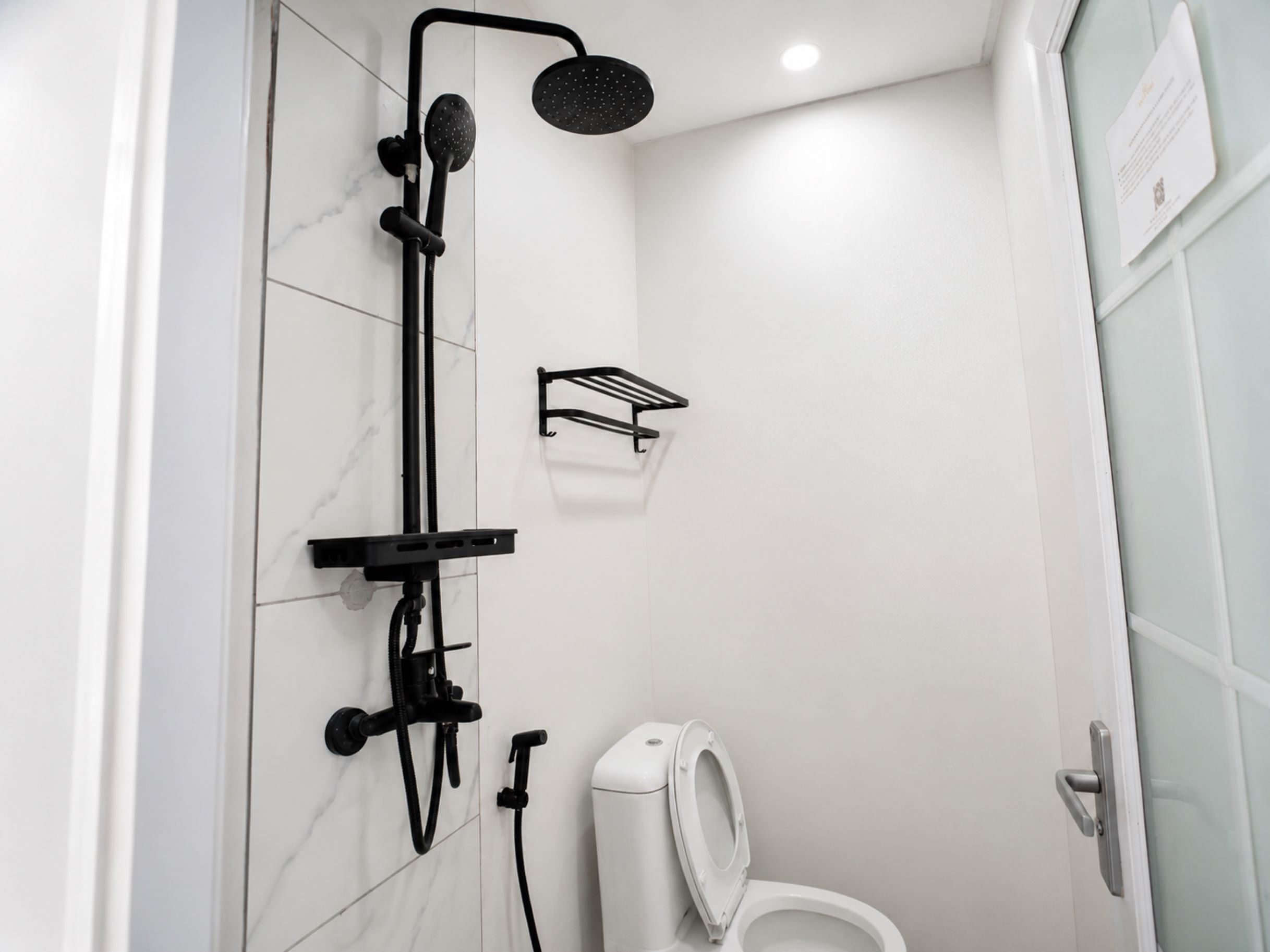 A modern bathroom with a shower, toilet, and a towel rack.