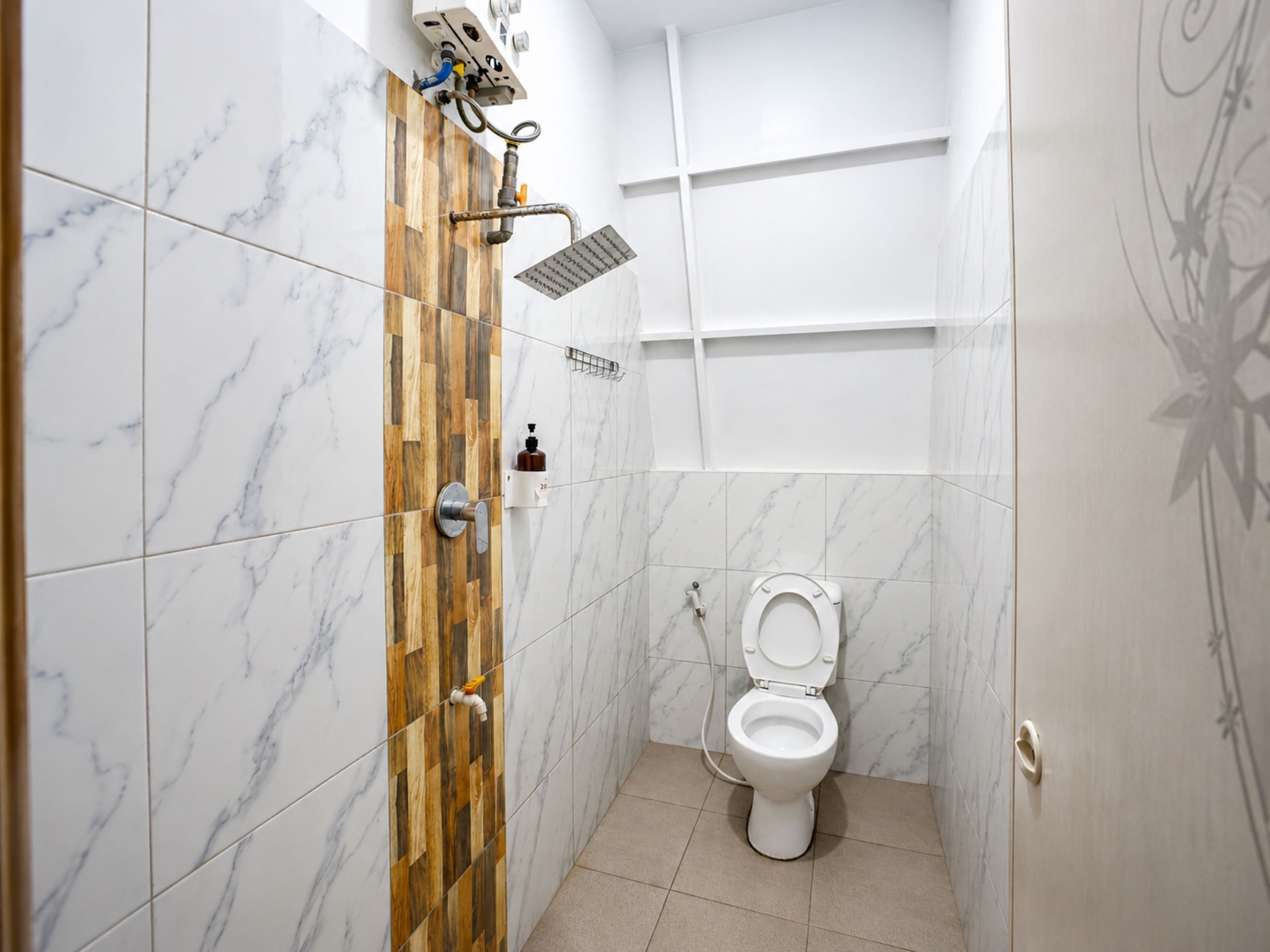 Baño con inodoro, ducha y pared de paneles de madera.