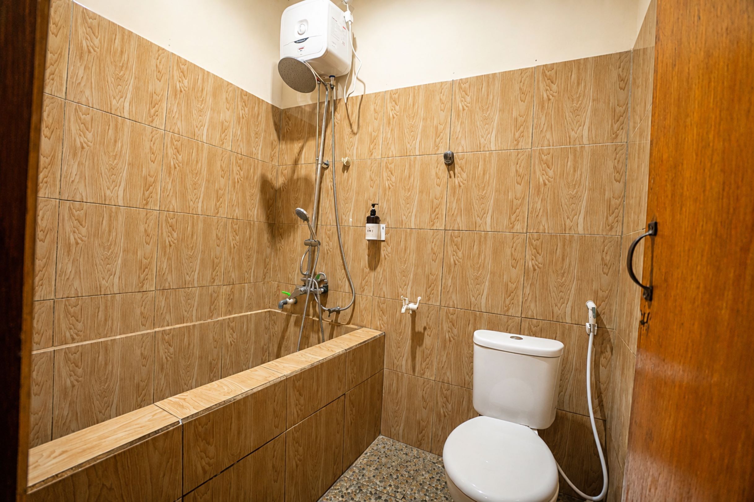 Un baño pequeño y funcional con ducha, inodoro y tocador de madera.
