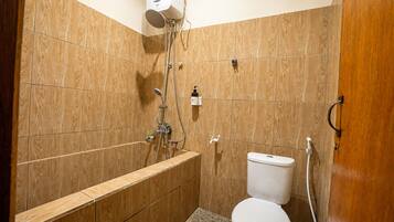 Un baño pequeño y funcional con ducha, inodoro y tocador de madera.