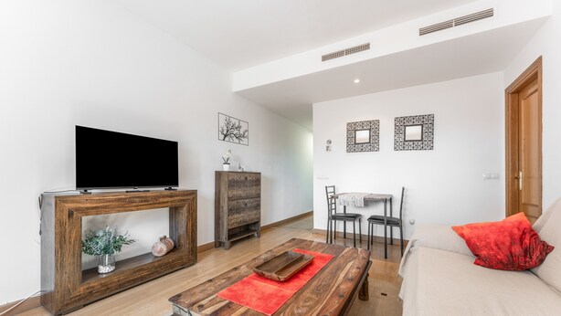 Un salon comprenant un téléviseur, une console en bois, un canapé et un coin repas.