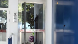 Un couloir avec une porte vitrée donnant sur une pièce, un mur bleu et un sol carrelé.