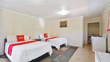 Una habitación de hotel con dos camas, un kitchenette pequeño, un baño y un cuadro en la pared.