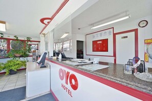 A reception desk with a 'OYO HOTEL' sign, a clock, and a menu board. - King Bed | Non-Smoking (Alpine TX)