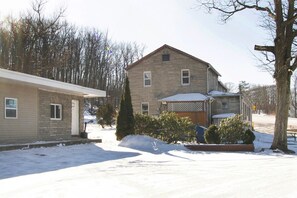 A two-story house with a stone facade, a snow-covered driveway, and a small garden area.
