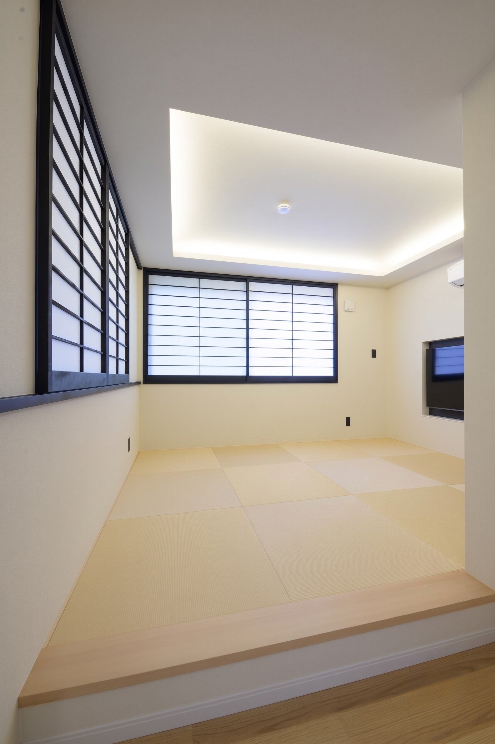 A room with tatami flooring, a sliding door, a television, and a ceiling light.