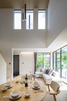 Un comedor moderno con una mesa de madera dispuesta para una comida, un sofá y vistas a zonas verdes.