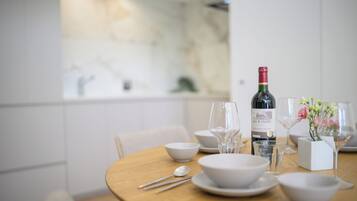 A dining table set with white bowls, wine glasses, and a bottle of wine.