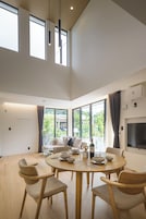 Un comedor moderno con una mesa redonda, sillas de madera y un ventanal que ofrece vistas al verdor.