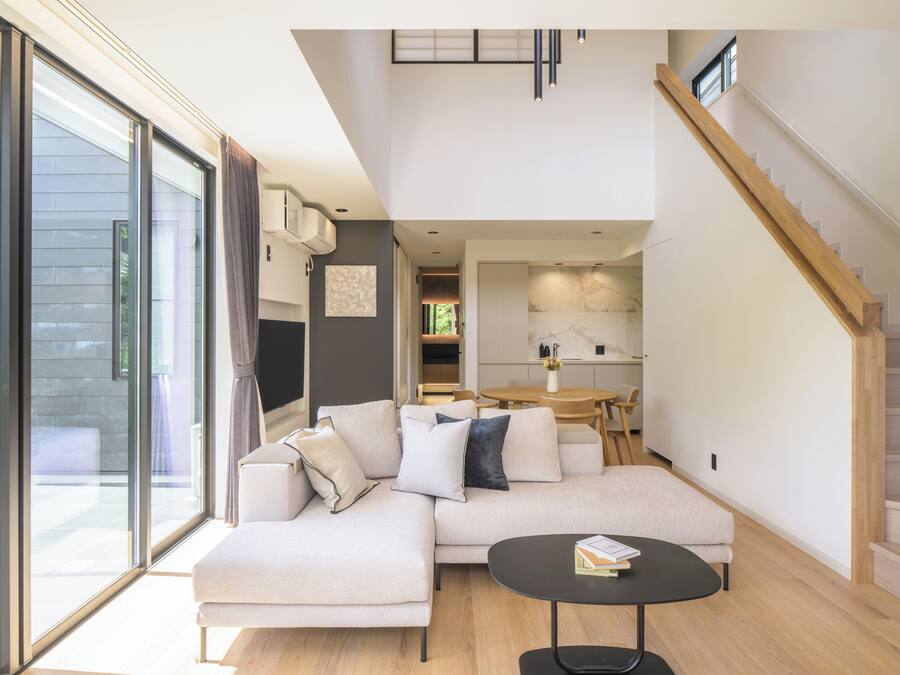 A modern living room with a sectional sofa, a round coffee table, and a staircase.