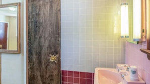 Un baño con puerta de madera, un lavabo y un espejo.