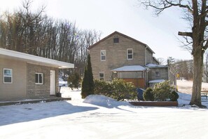 A two-story house with a stone facade, a front porch, and a snow-covered yard.