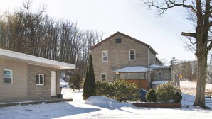 A two-story house with a stone facade, a front porch, and a snow-covered yard. - 2 Queen Bed|Non-Smoking (Wilkes-Barre PA)