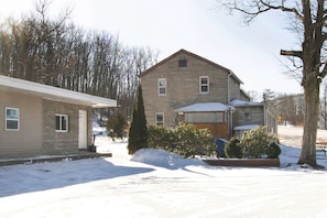 A two-story house with a stone facade, a front porch, and a snow-covered yard.