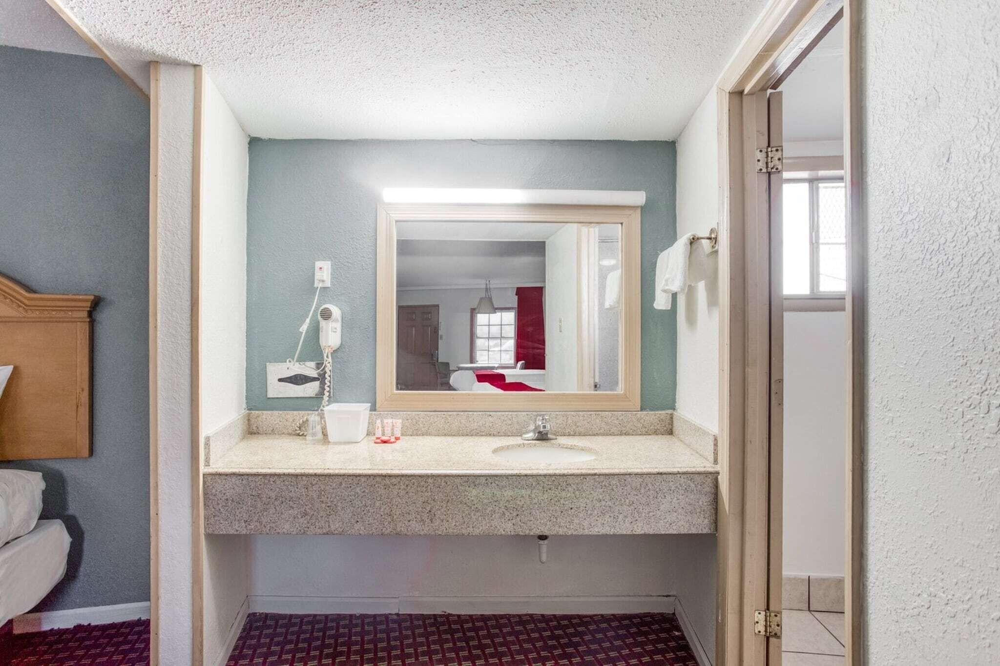 Un baño con lavamanos, espejo y perchero para toallas.