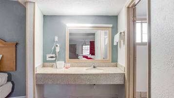 Un baño con lavamanos, espejo y perchero para toallas.