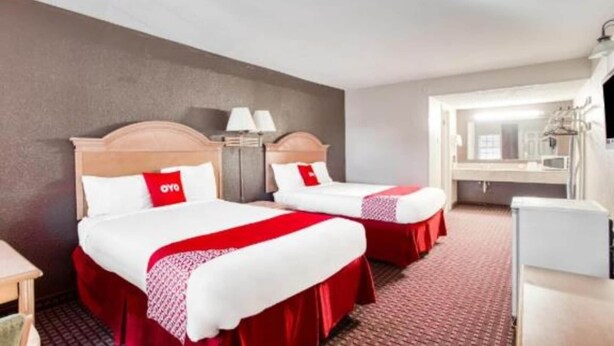 Hotellihuone, jossa on kaksi sänkyä, työpöytä, peili ja pieni keittokomero.
