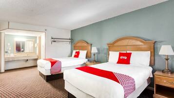 A hotel room with two beds, a mirror, bedside lamps, and a patterned carpet.