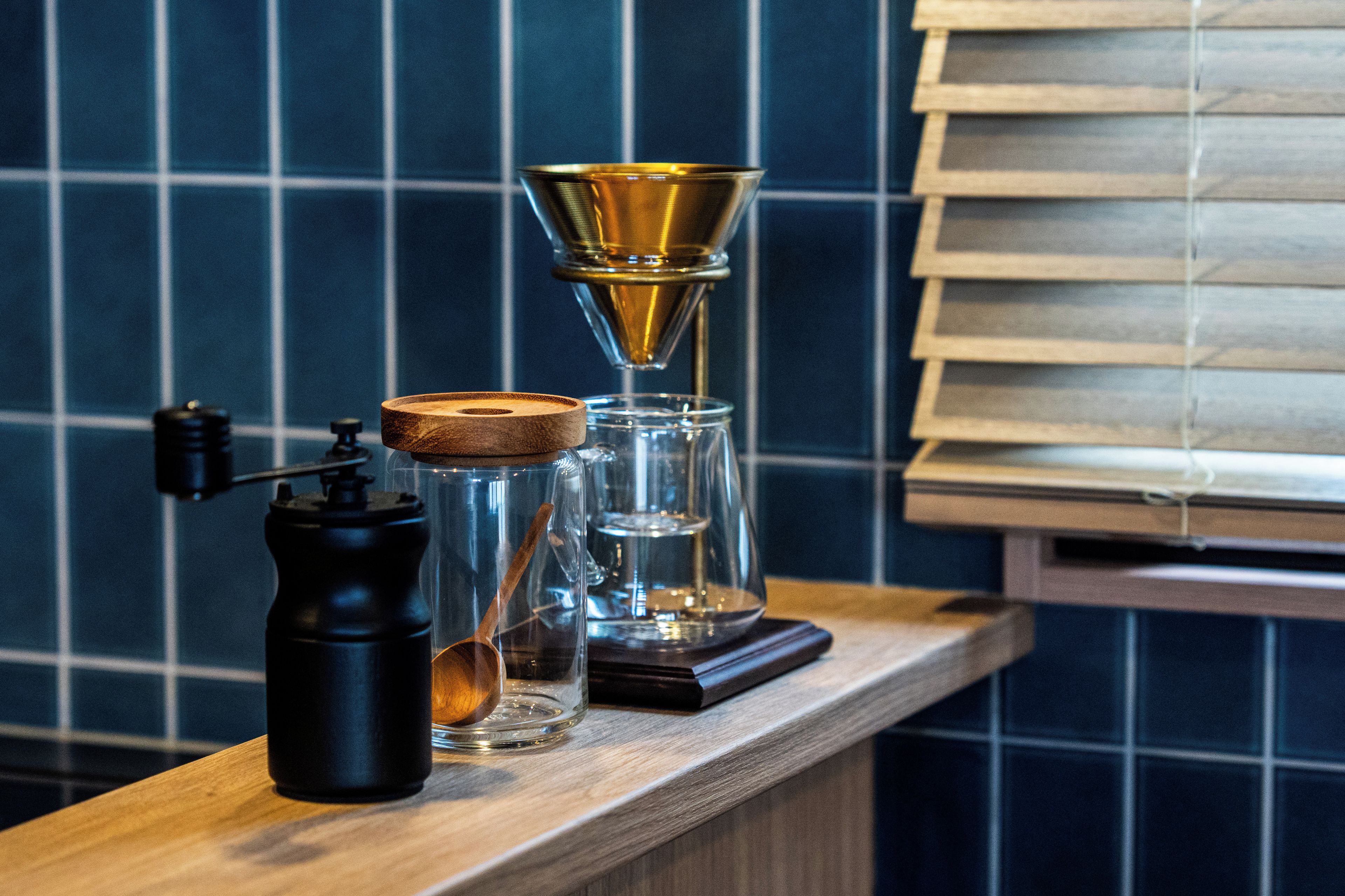 Una encimera de cocina con un molinillo de café, una jarra de vidrio y un gotero para café.