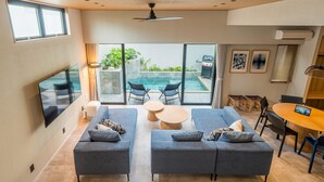 A modern living room with a pool, two sofas, a dining table, and a ceiling fan.