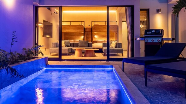 A modern outdoor living area with a pool, seating, and a barbecue grill.