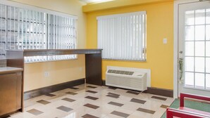 Una habitación con piso a cuadros, un escritorio, un radiador y dos ventanas con persianas.