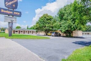 A Budget Inn with a signboard, a parking lot, and a building with a green lawn.